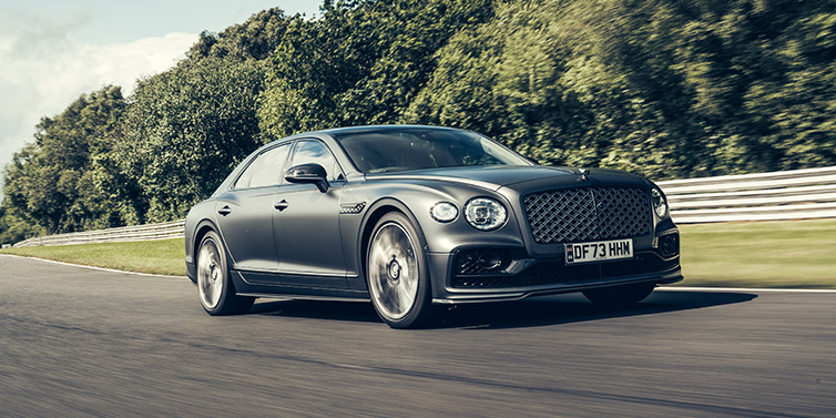 Bentley Sydney Bentley Flying Spur Mulliner sedan front three quarter in dark grey paint driving dynamically by some trees on a track