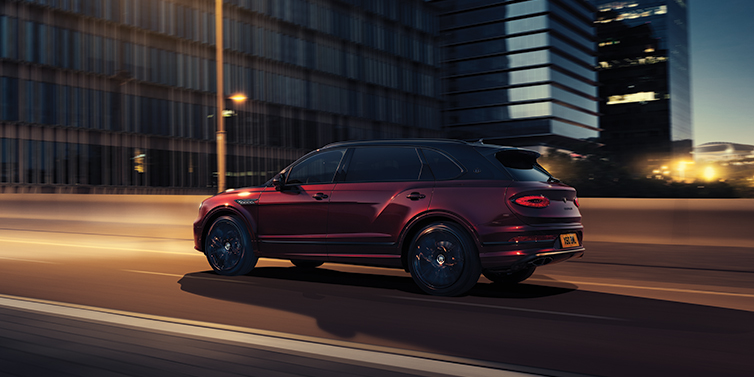 Bentley Sydney Bentley Bentayga Extended Wheelbase Mulliner SUV in Cricket Ball red paint driving dynamically in city at night